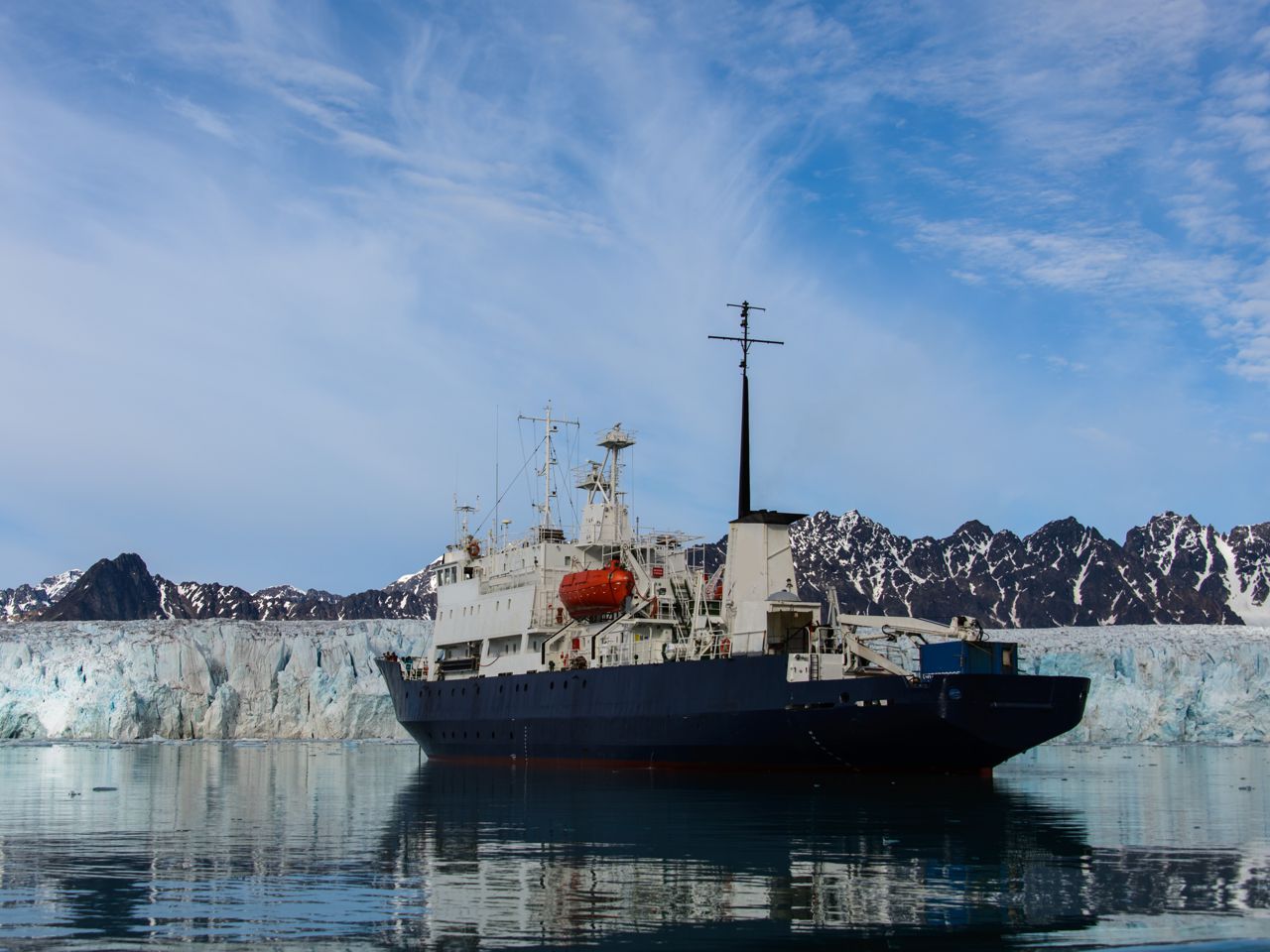 Icebreaker on the water in front of ice and mountain landscape